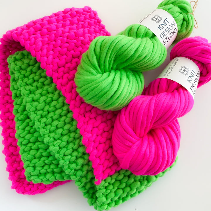 Colorful scarf in pink and green hand knitted from chunky merino wool yarn.