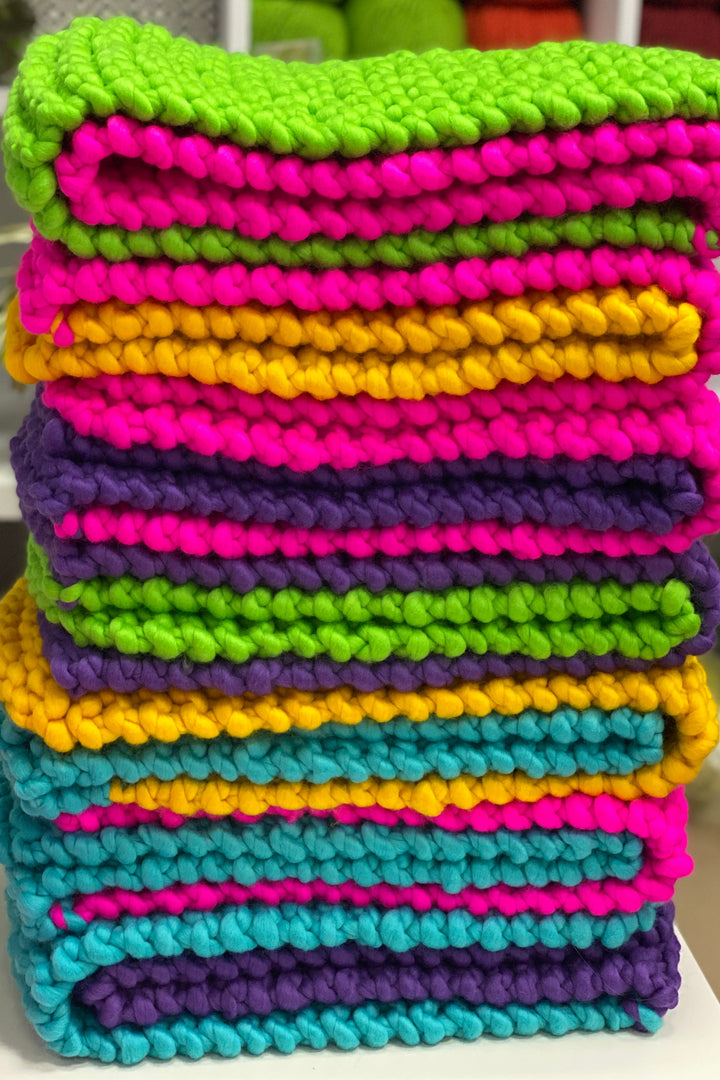 Colorful scarf stacked with vibrant pink, yellow, green, blue, and purple hues made of soft chunky merino wool.