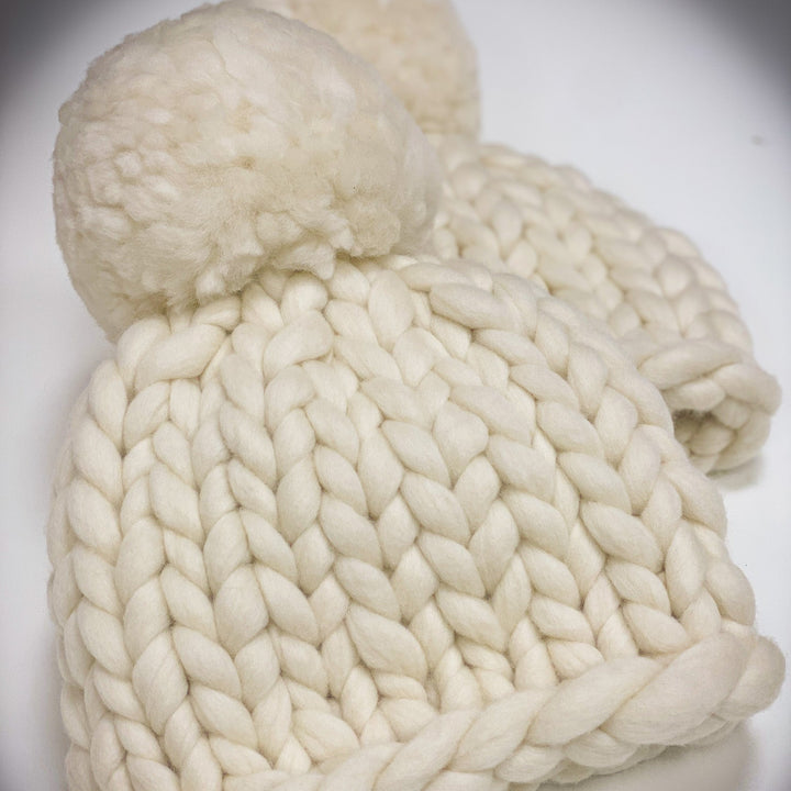 White knitted beanie with pom-poms on a white background